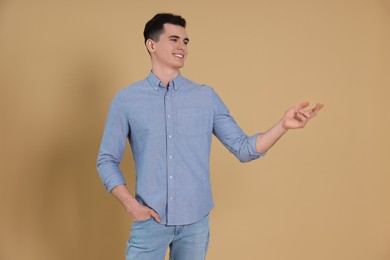 Photo of Portrait of handsome young man gesturing on beige background