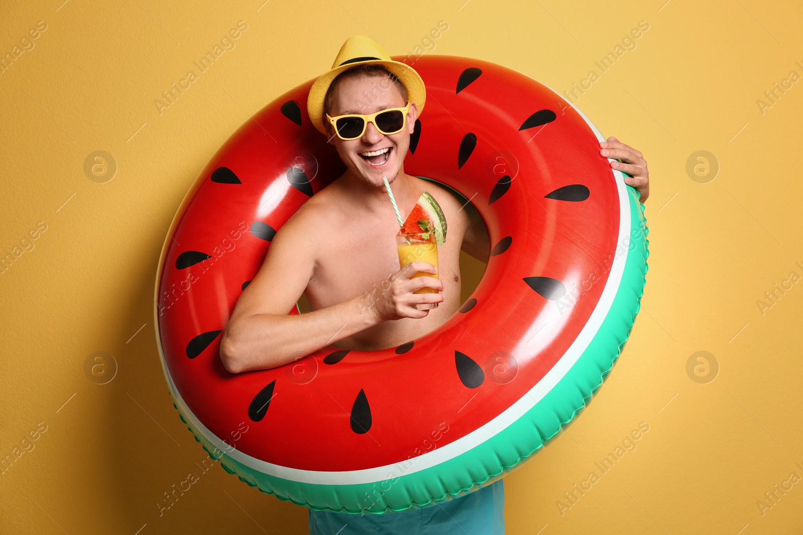 Photo of Shirtless man with inflatable ring and cocktail on color background