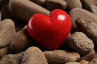 Photo of One red decorative heart on stones, closeup