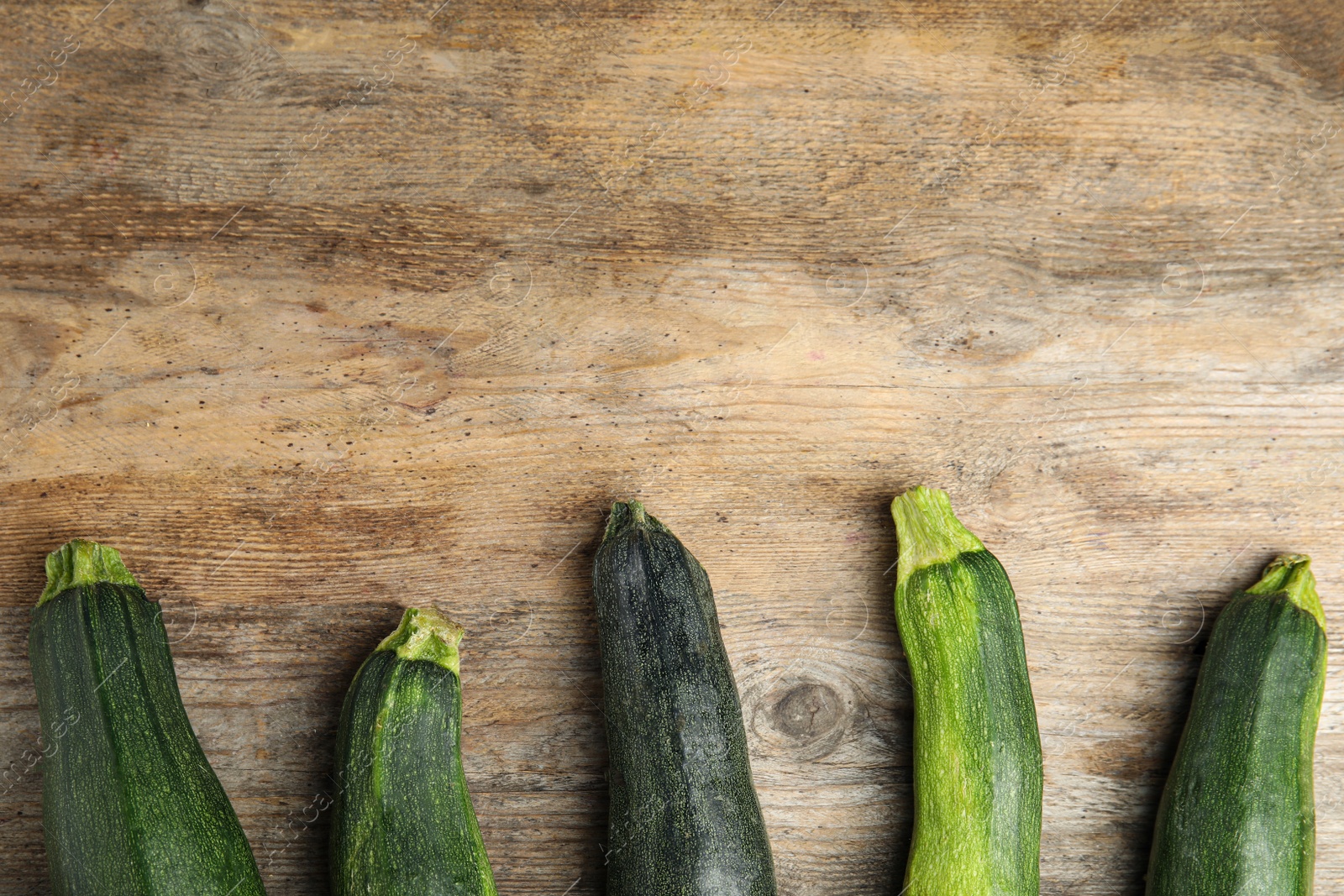 Photo of Fresh ripe green zucchini on wooden background, flat lay. Space for text