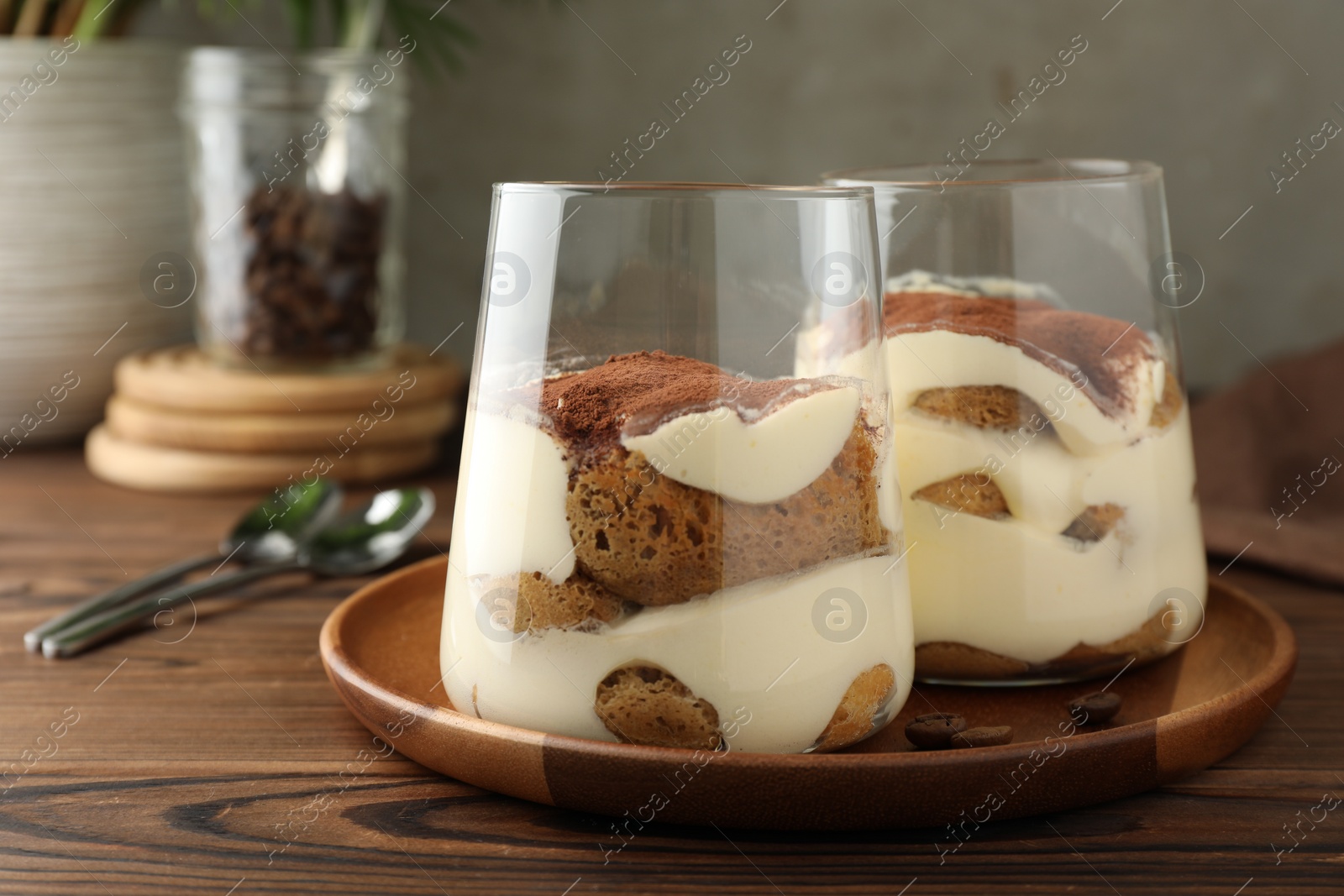 Photo of Delicious tiramisu in glasses on wooden table, closeup