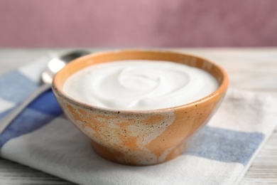 Bowl with yummy yogurt on wooden table