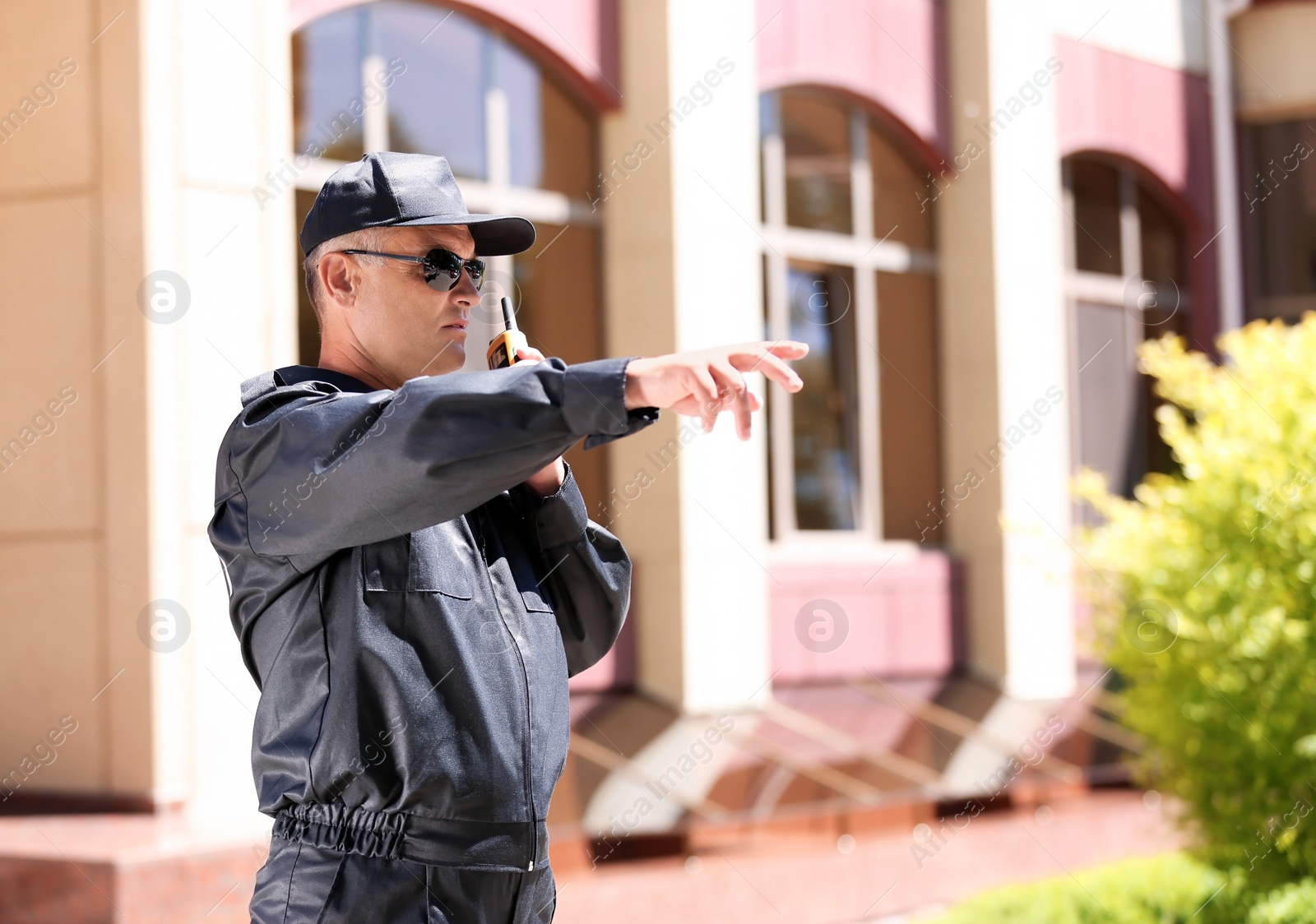 Photo of Male security guard using portable radio transmitter outdoors