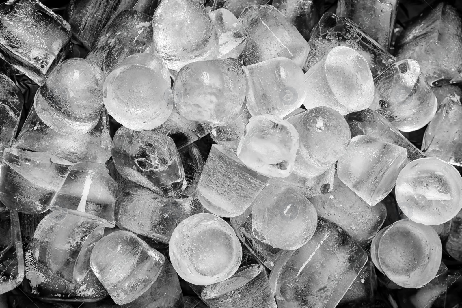 Photo of Many pieces of ice on black background, top view