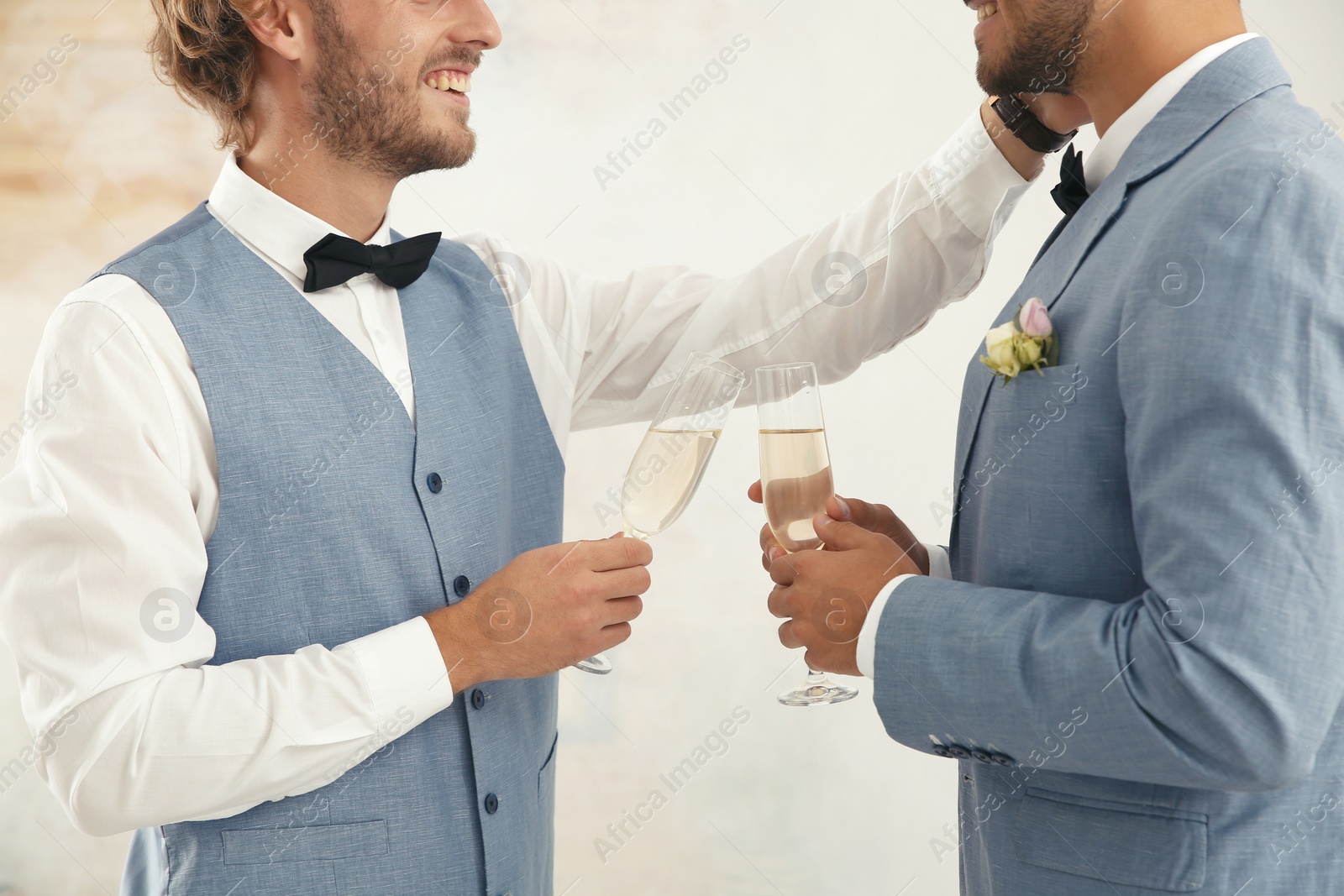 Photo of Newlywed gay couple with glasses of champagne at home, closeup