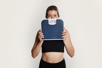 Woman in sportswear with scales on gray background