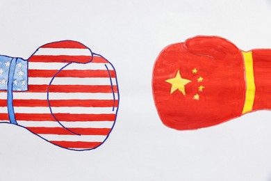 Photo of Boxing gloves with American and Chinese flags drawn on white paper, top view. Trade war