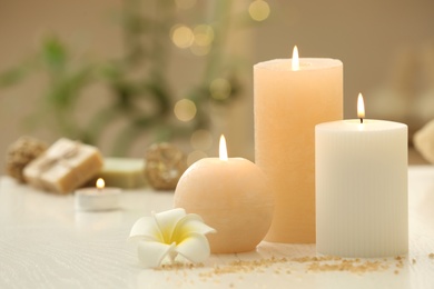 Photo of Burning candles on white table indoors. Space for text