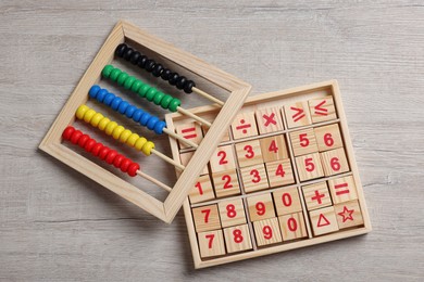 Math game with numbers and colorful toy abacus on white wooden table, flat lay