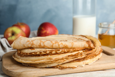 Stack of fresh thin pancakes on wooden board, closeup