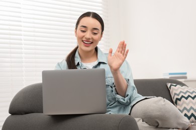 Woman having video chat via laptop on couch at home