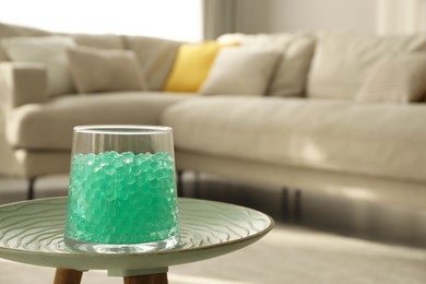 Photo of Mint filler in glass vase on table at home, space for text. Water beads