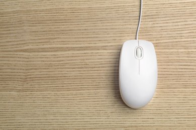 Photo of Wired computer mouse on wooden background, top view. Space for text