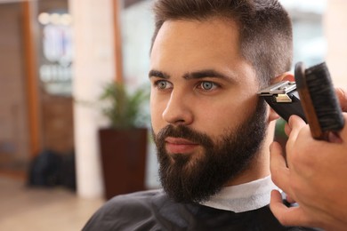 Photo of Professional hairdresser working with client in barbershop, closeup