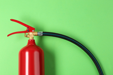 Fire extinguisher on green background, top view