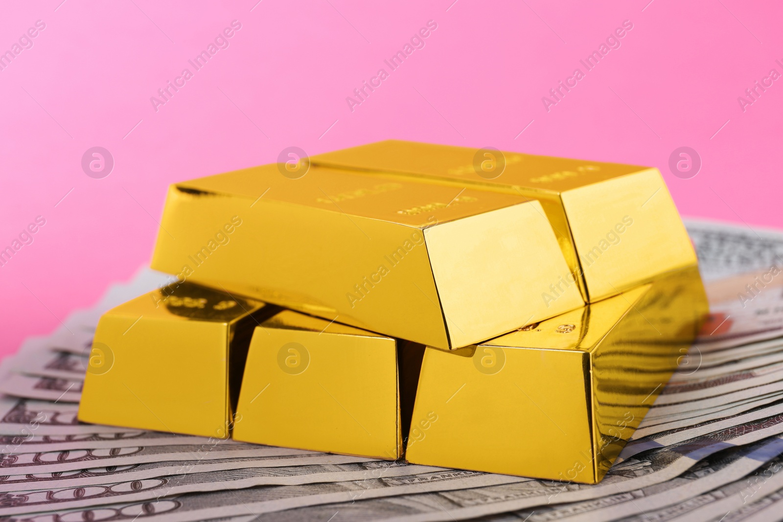 Photo of Shiny gold bars and dollar bills on color background