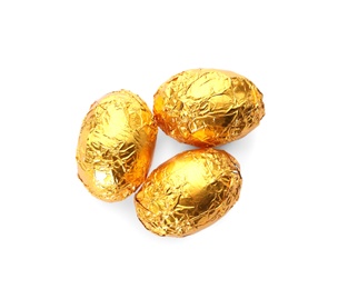 Chocolate eggs wrapped in golden foil on white background, top view