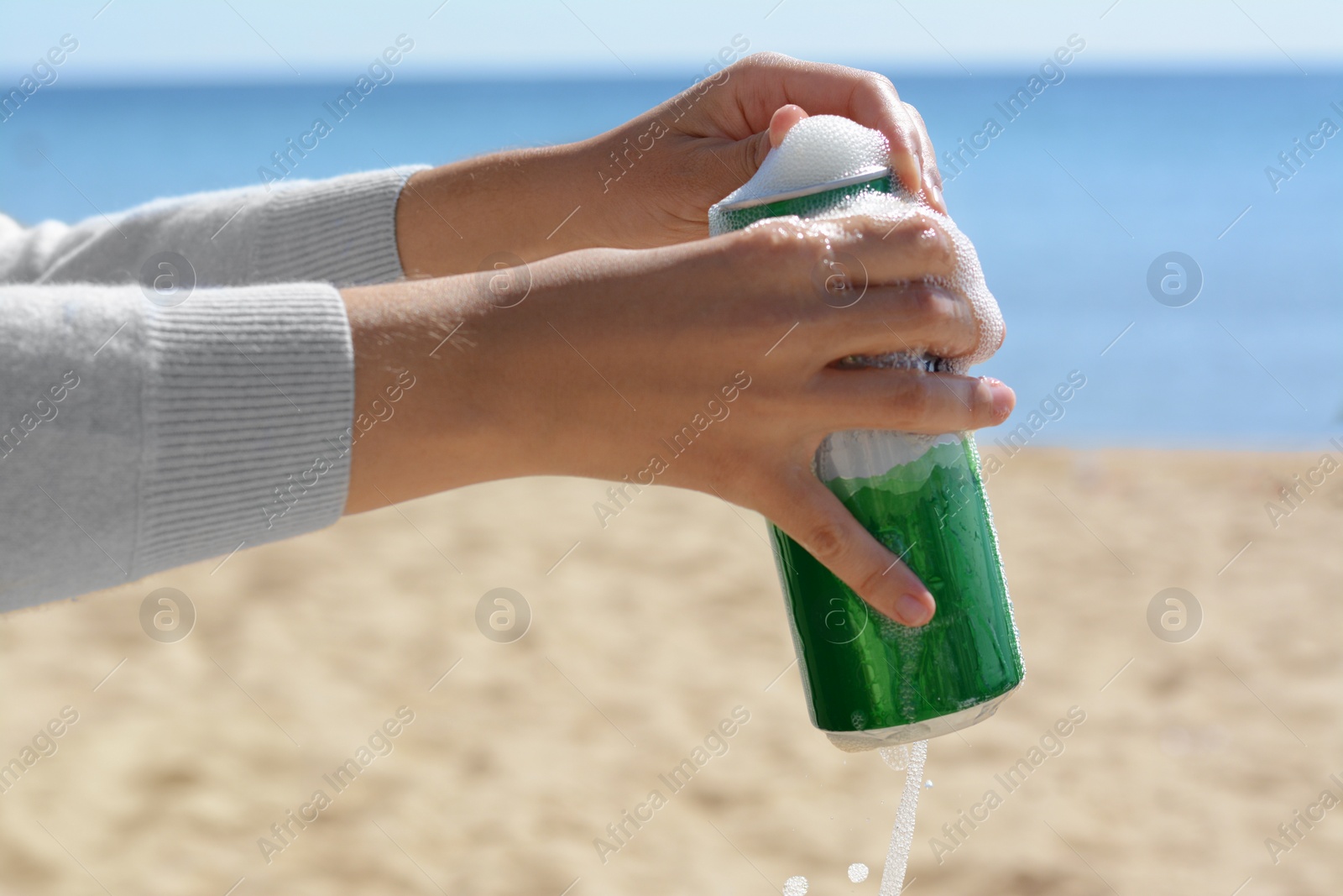 Photo of Woman opening can with sparkling drink at beach, closeup