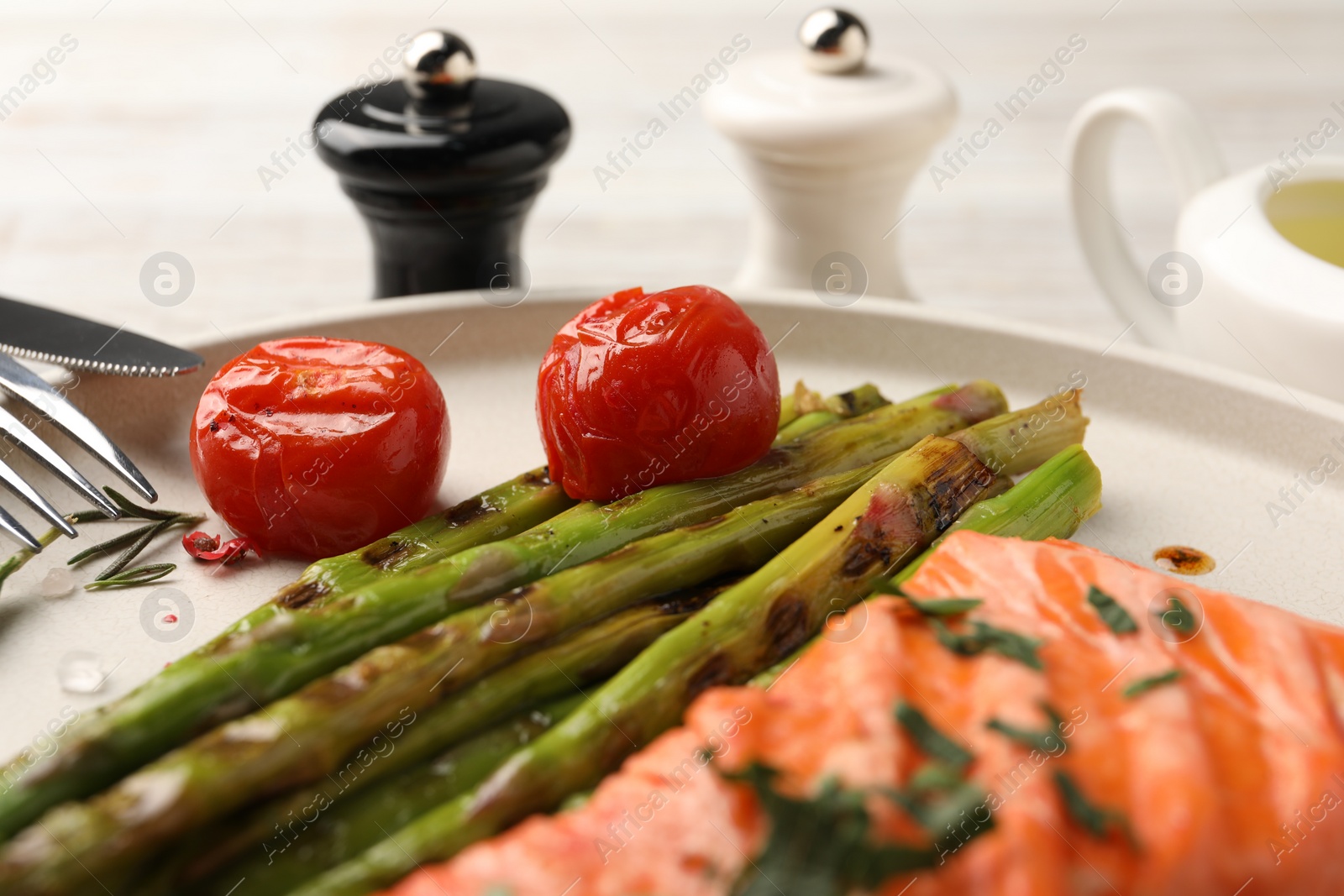 Photo of Tasty grilled salmon with tomatoes, asparagus and spices on table, closeup