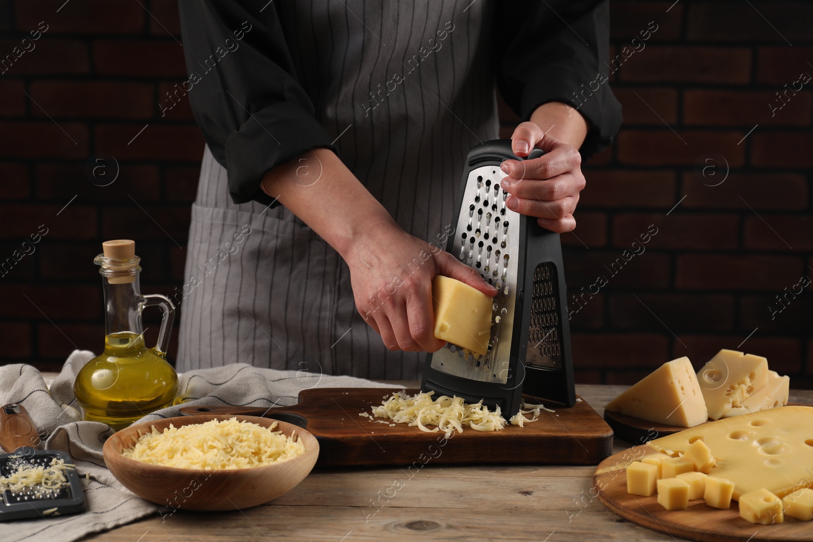 Photo of Woman grating cheese at wooden table, closeup