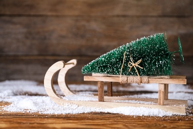 Sleigh with decorative Christmas tree on wooden table