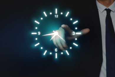 Image of Man holding virtual icon of clock on dark background, closeup. Time management