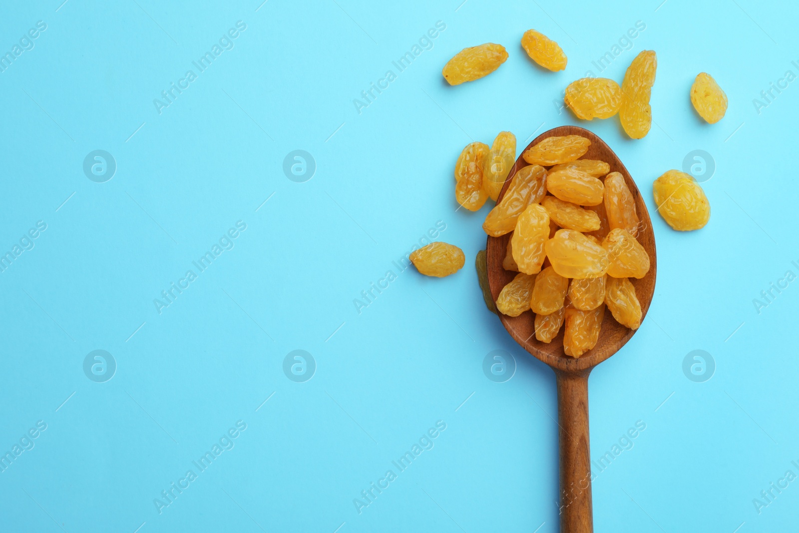 Photo of Spoon of raisins on color background, top view with space for text. Dried fruit as healthy snack
