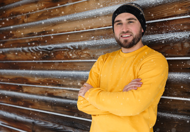 Photo of Young man wearing warm clothes near wooden wall.  Winter vacation
