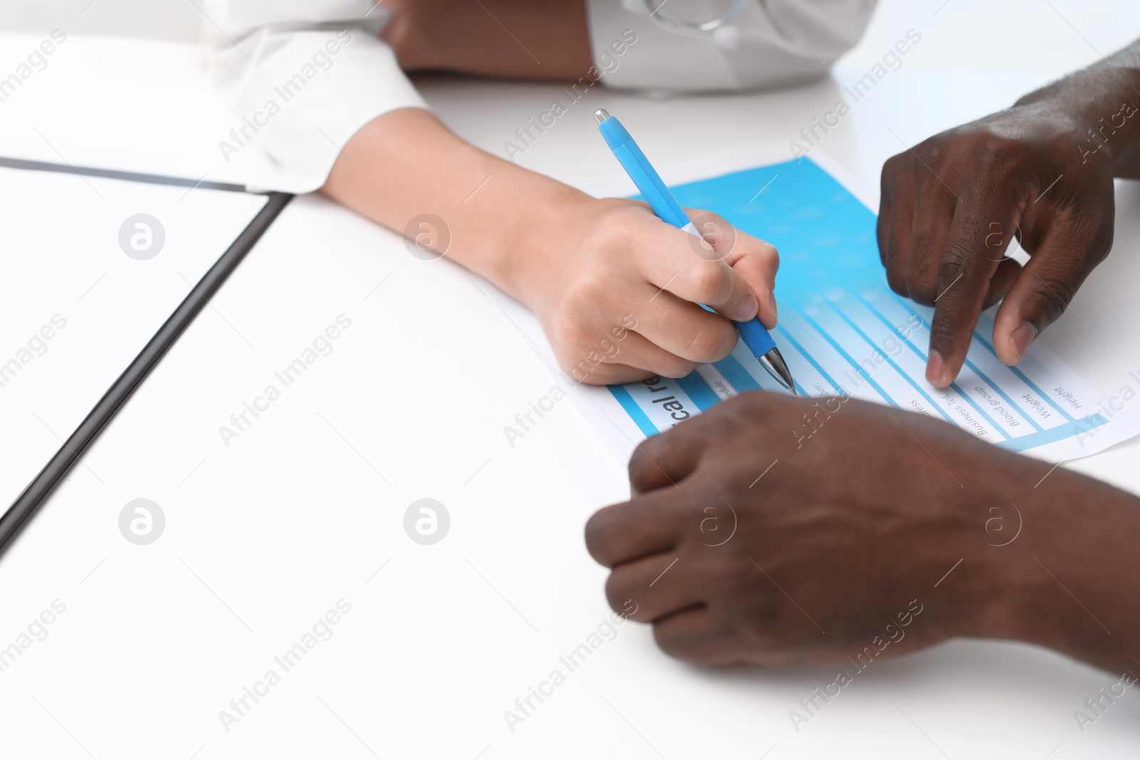 Photo of Young doctor consulting African-American patient in hospital