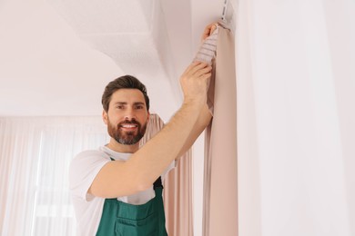 Photo of Worker in uniform hanging window curtain indoors