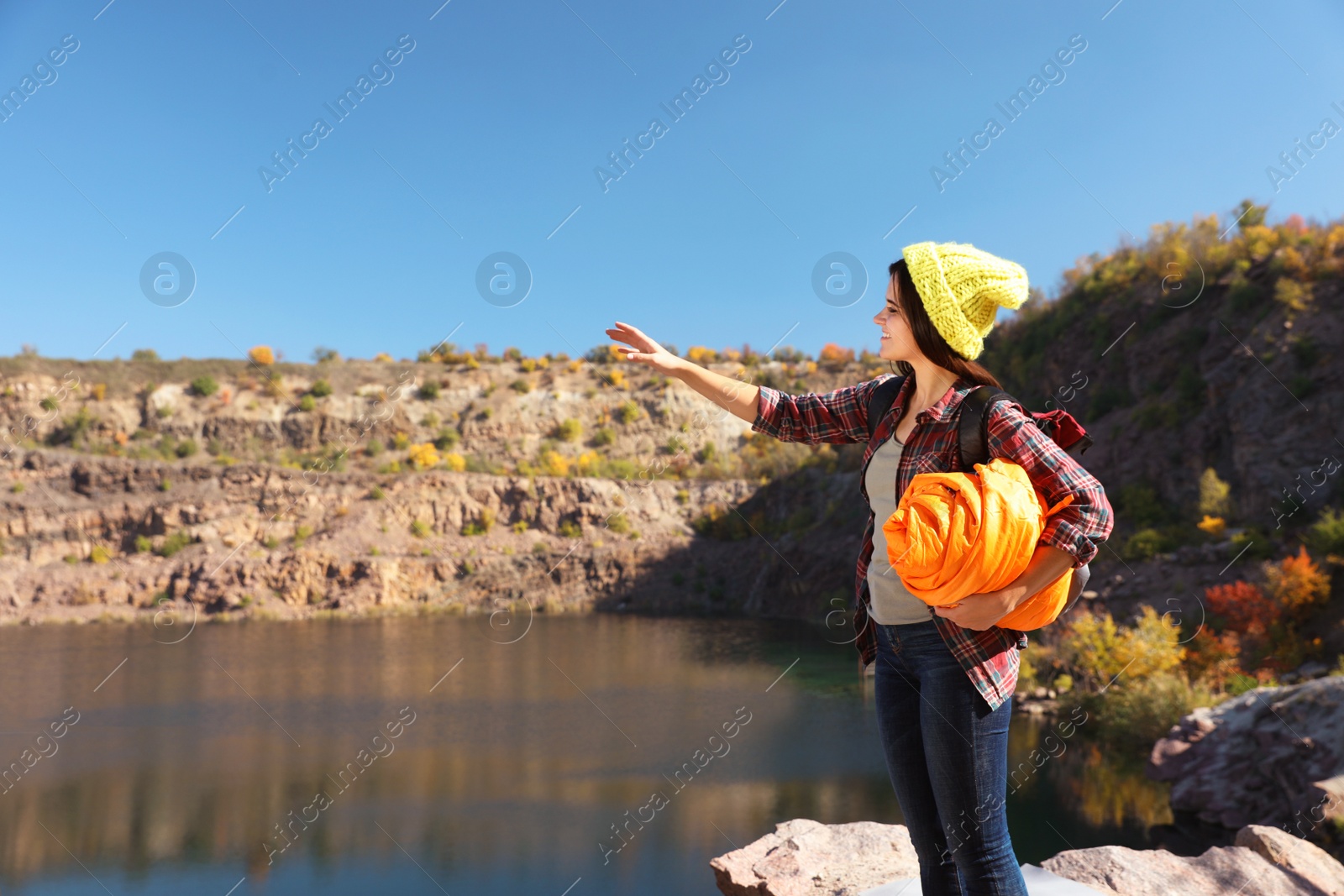 Photo of Female camper with sleeping bag near beautiful lake. Space for text