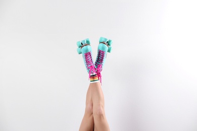 Young woman with retro roller skates on white background, closeup