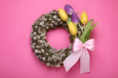 Photo of Wreath made of beautiful willow, colorful tulip flowers and bow on pink background, top view