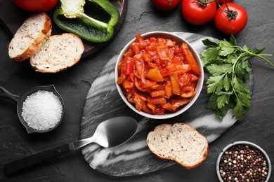 Delicious lecho and ingredients on black table, flat lay