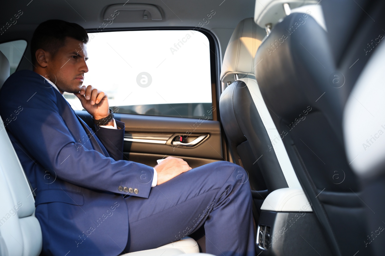 Photo of Handsome man sitting on backseat of modern car