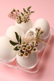 Photo of Festive composition with eggs and floral decor on pink background. Happy Easter