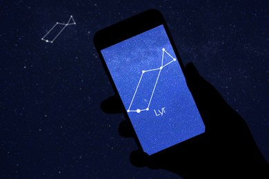 Woman using stargazing app on her phone at night, closeup. Identified stick figure pattern of Lyra constellation on device screen
