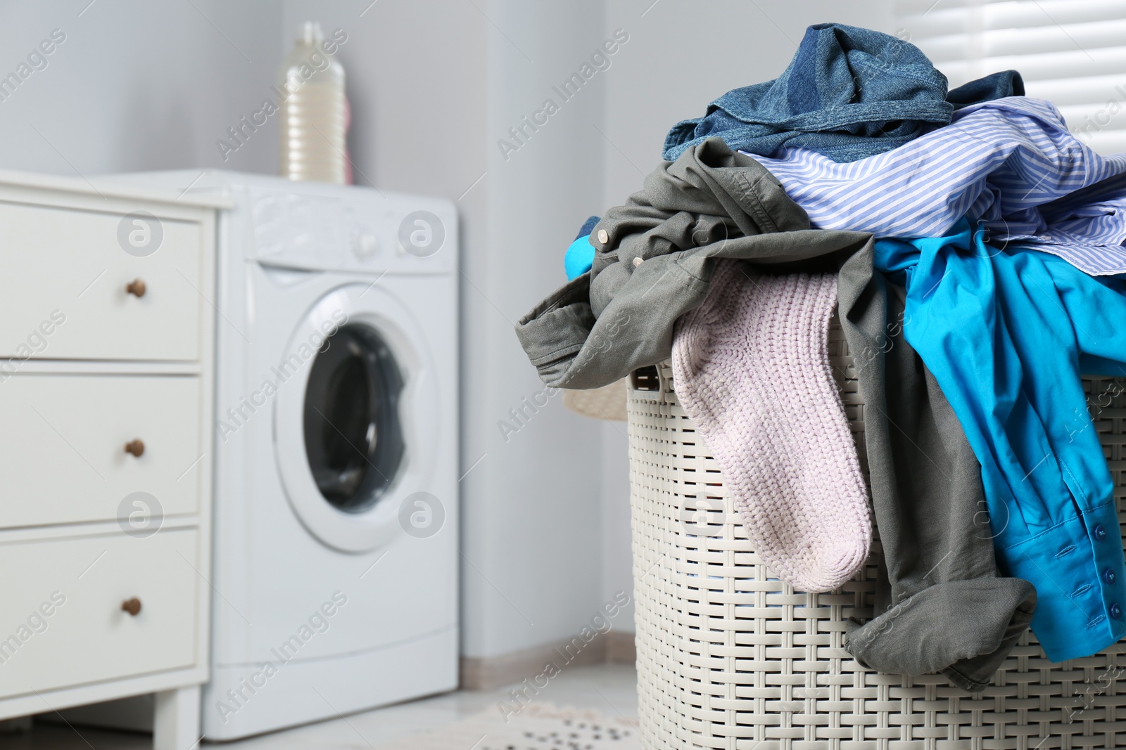 Photo of Plastic laundry basket overfilled with clothes in bathroom, closeup. Space for text