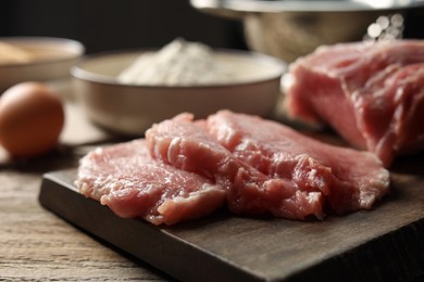 Photo of Cooking schnitzel. Raw pork slices on wooden table, closeup