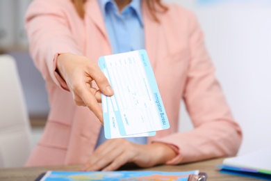 Photo of Female consultant holding tickets in travel agency, closeup