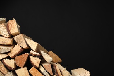 Photo of Cut firewood on black background. Space for text