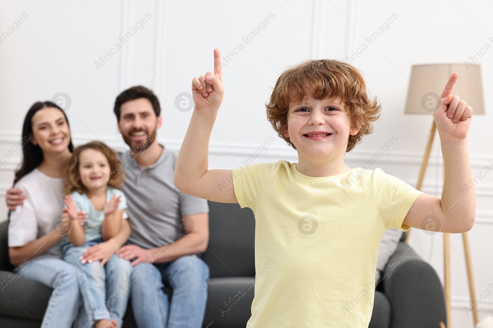 Photo of Happy family having fun at home. Son dancing while his relatives resting on sofa