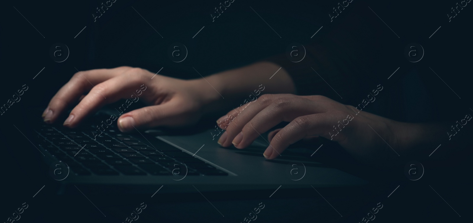 Image of Woman working on computer at table in darkness, closeup. Banner design