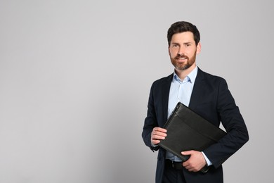 Photo of Handsome real estate agent with documents on grey background, space for text