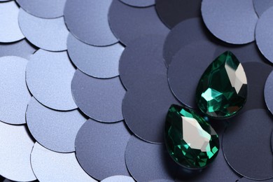 Photo of Beautiful green gemstones for jewelry on sequin fabric, above view. Space for text