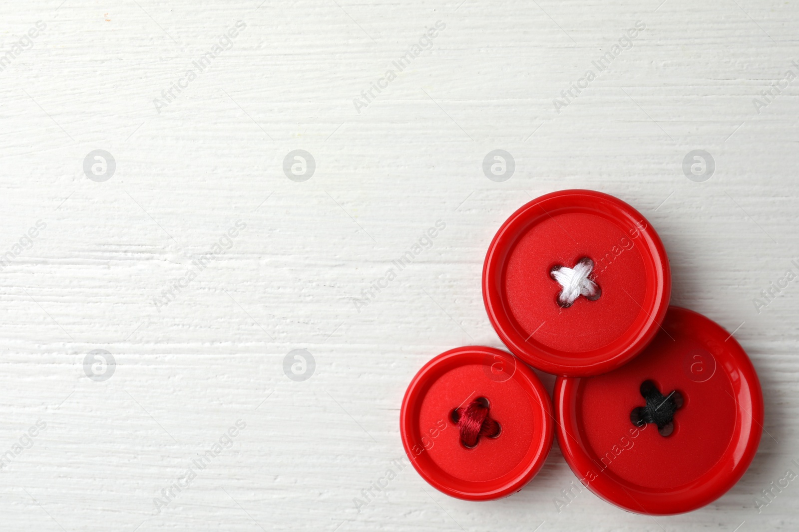 Photo of Red sewing buttons on white wooden background, flat lay. Space for text