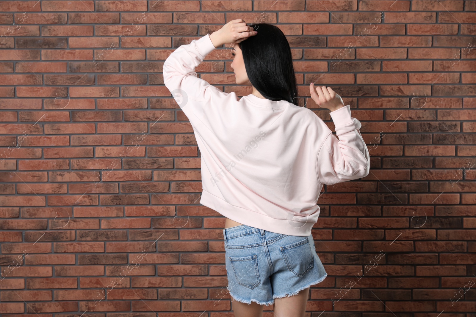 Photo of Young woman in sweater at brick wall. Mock up for design