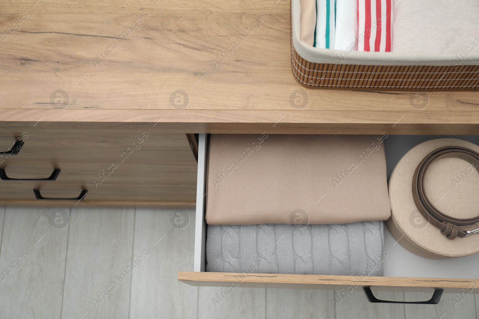 Photo of Chest of drawers with different folded clothes and accessories indoors, top view