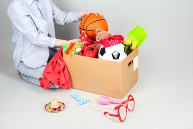 Photo of Woman with box of unwanted stuff on grey background, closeup