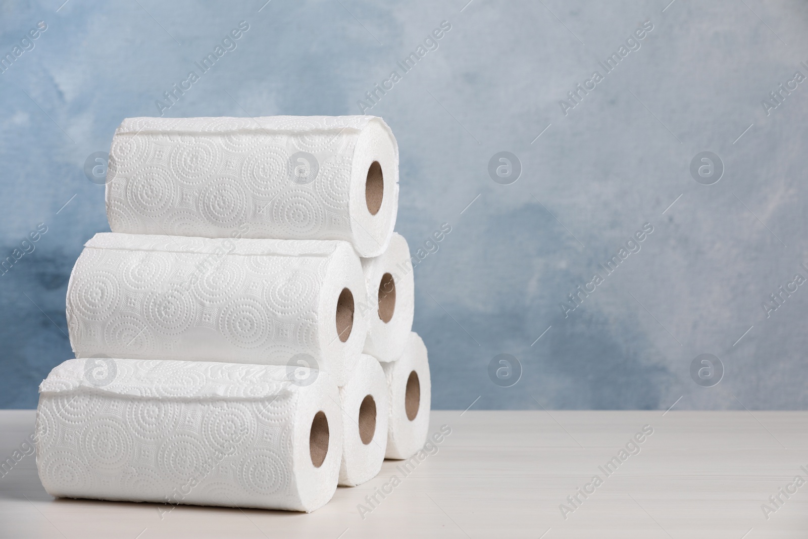 Photo of Many rolls of paper towels on white wooden table. Space for text